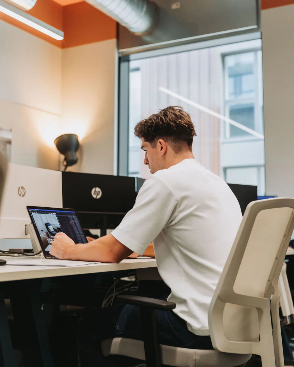 Person working on a laptop at a desk in an office setting
