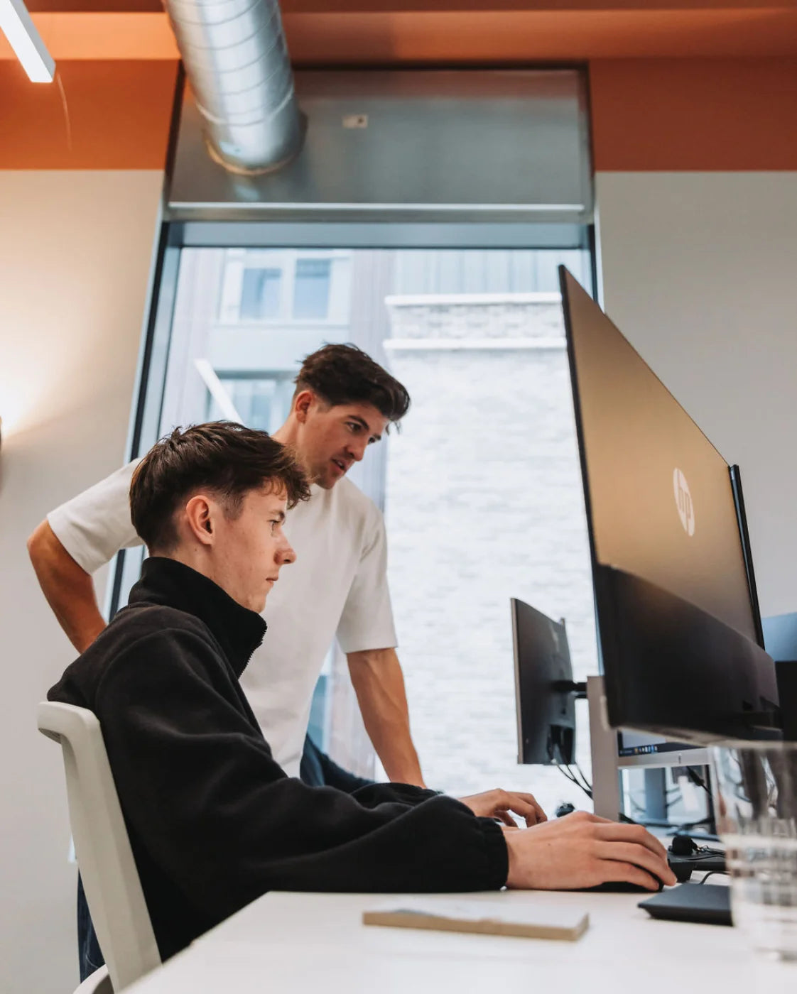 Two people working together at a computer in an office setting.