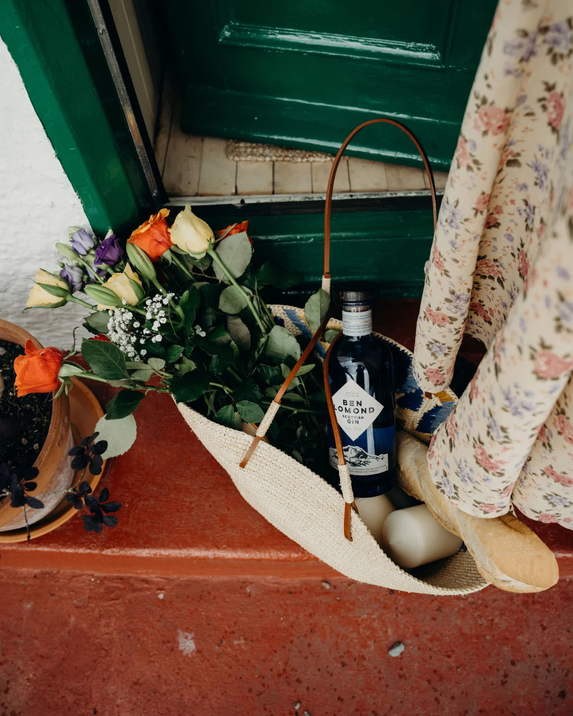 Bottle of Gin and tonic with flowers in a bag on a step