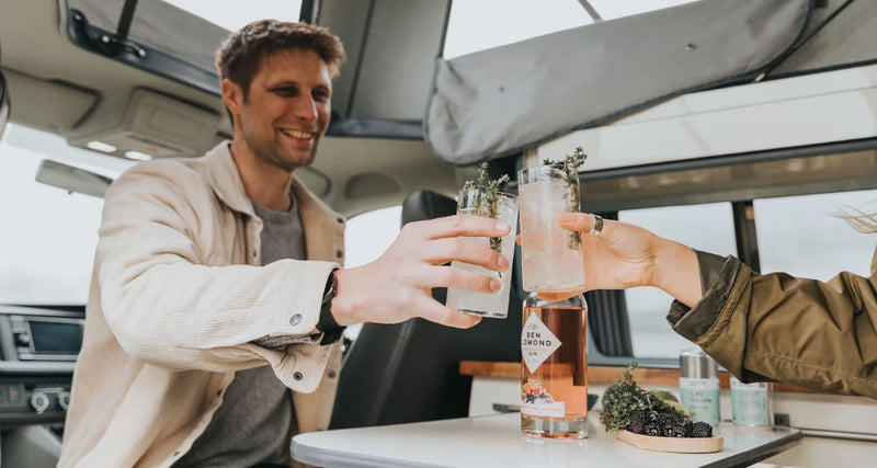 Two people inside a vehicle, clinking glasses with drinks.