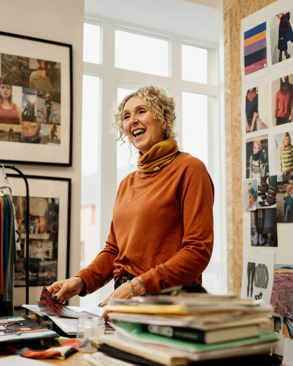 Woman standing in a room with books and a wall of photos