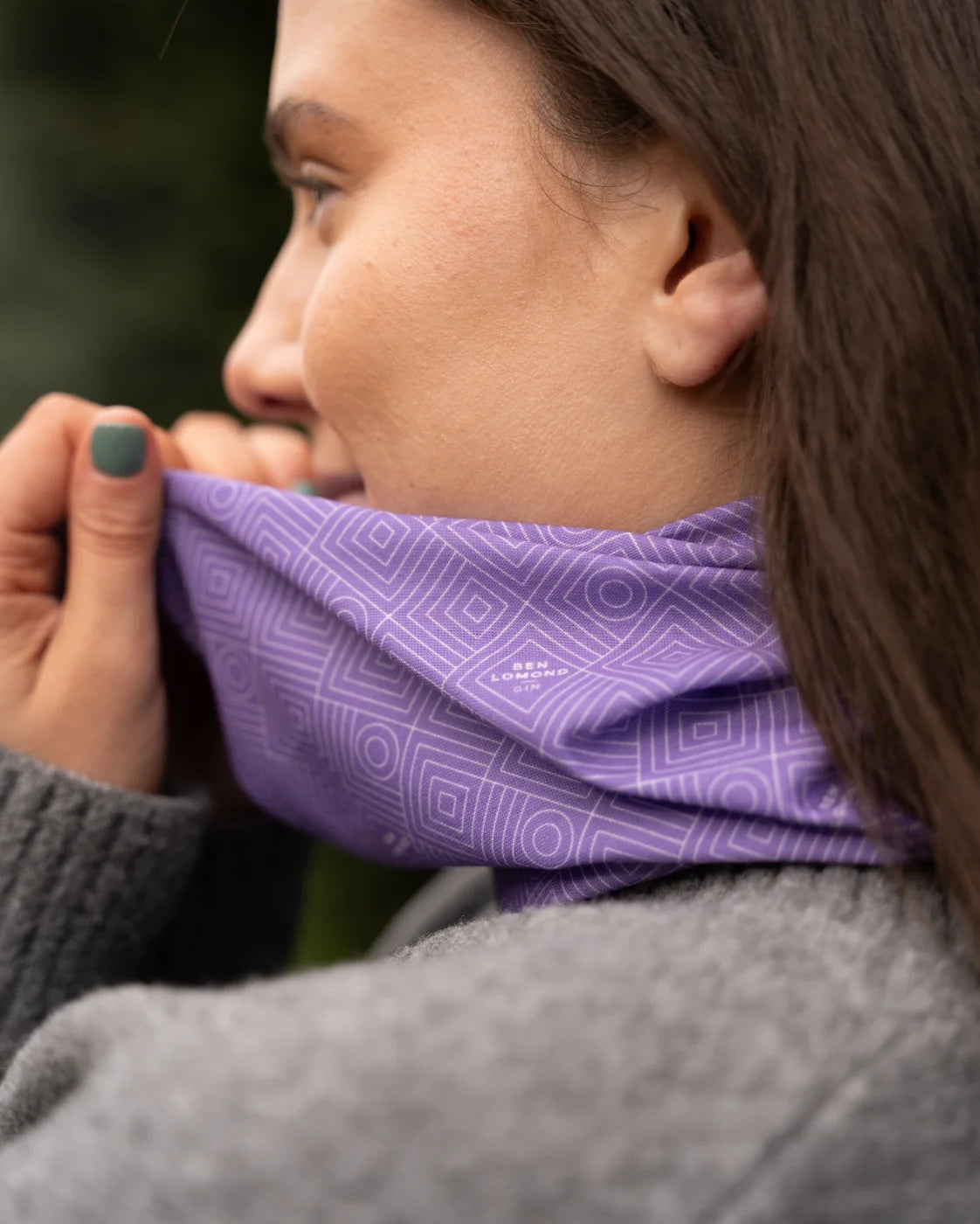 Person wearing a purple patterned scarf, with a blurred natural background