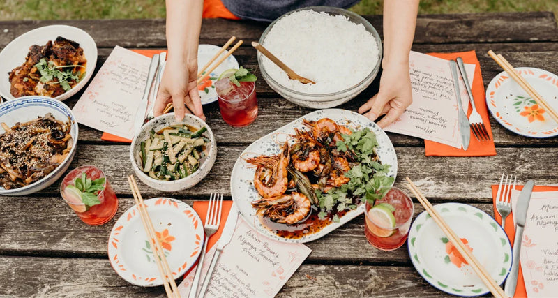 Diverse food platter with shrimp, vegetables, and drinks on a wooden table.