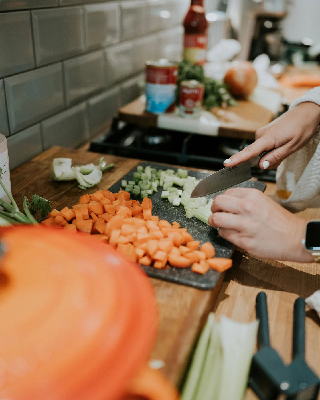 Person chopping vegetables on a cutting board with a kitchen background
