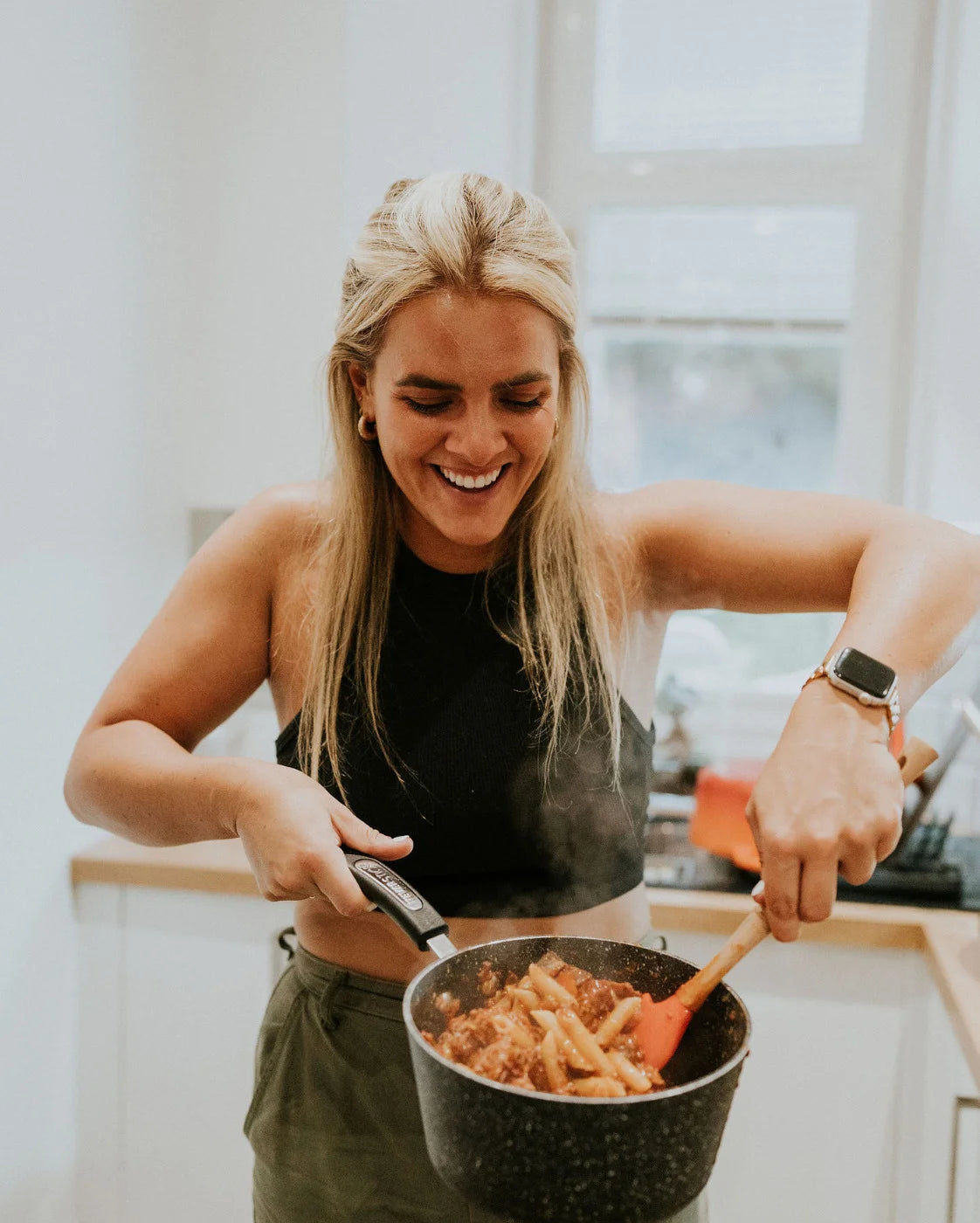 Woman cooking pasta in a pan in a kitchen