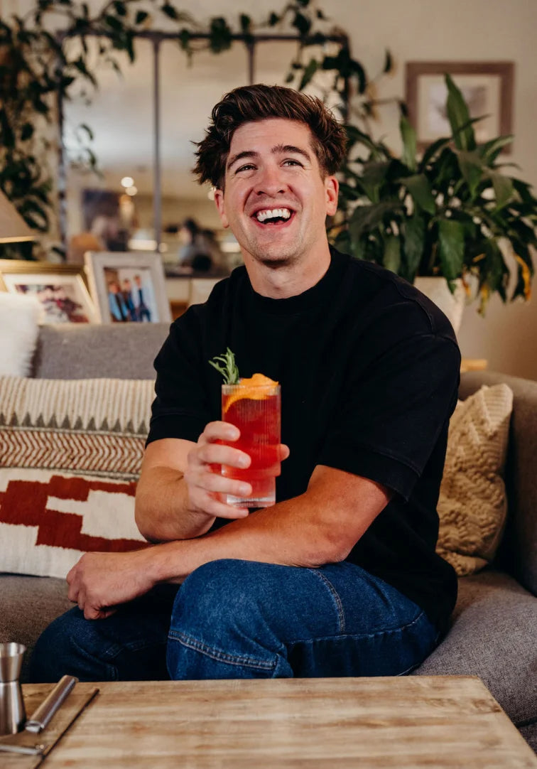 Man holding a colorful drink in a cozy living room