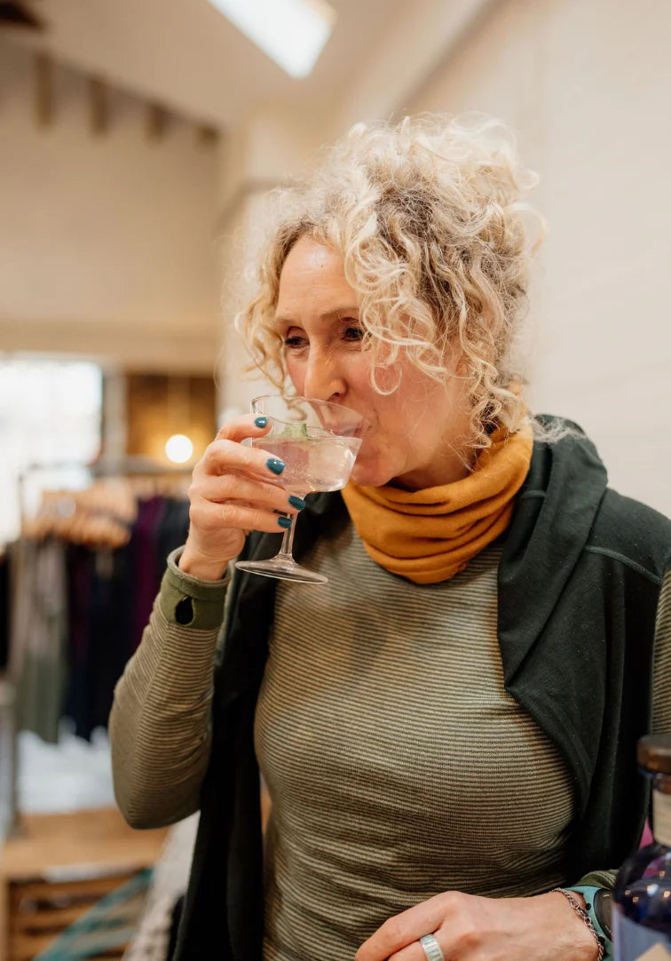 Woman drinking from a glass in a store setting