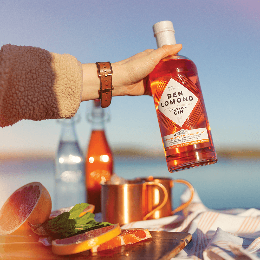 Bottle of Ben Lomond Scottish Gin held by a hand with a scenic background