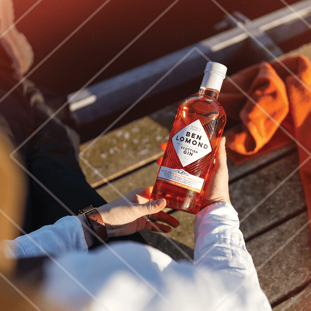 Person holding a bottle of Ben Lomond Gin by a fire