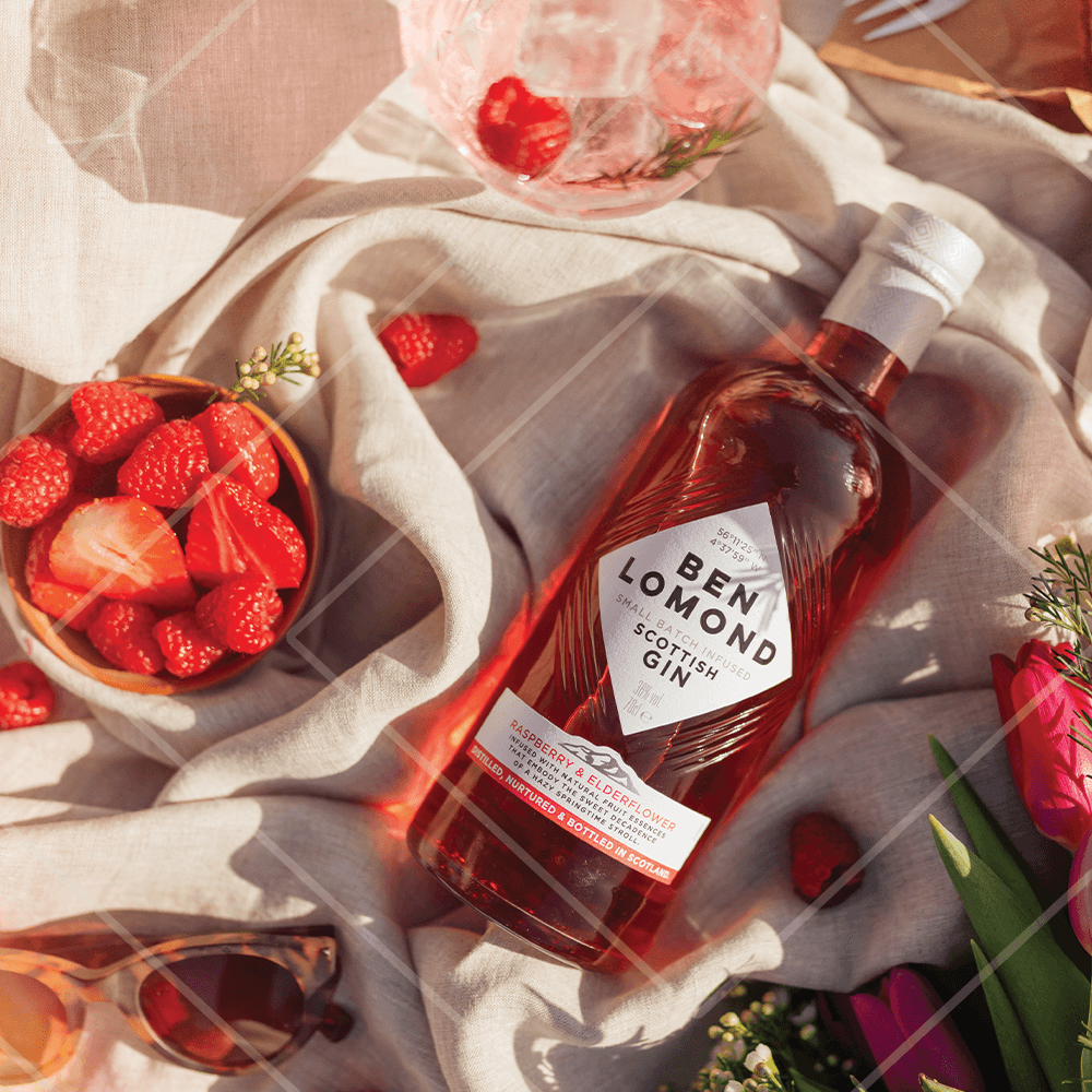 Bottle of Ben Lomond Scottish Gin surrounded by strawberries and sunglasses on a light fabric background