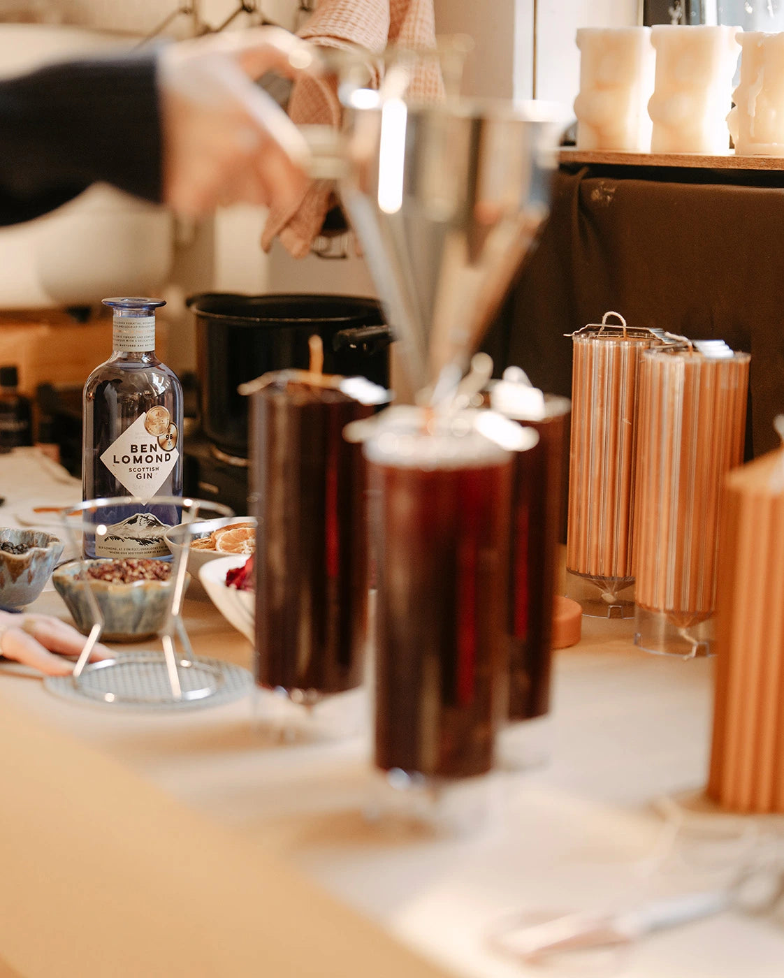 Candle making with bottles and glasses on a bar counter