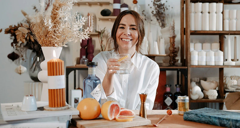 Woman holding a gin & tonic with lemon slices in a store setting