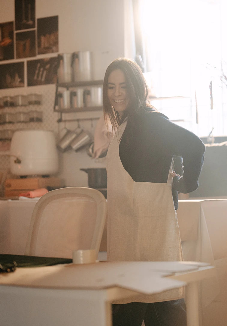 Woman in a kitchen wearing an apron, smiling.