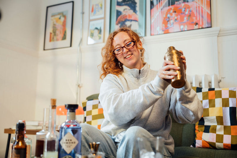 Person sitting on a couch holding a bottle in a cozy living room.