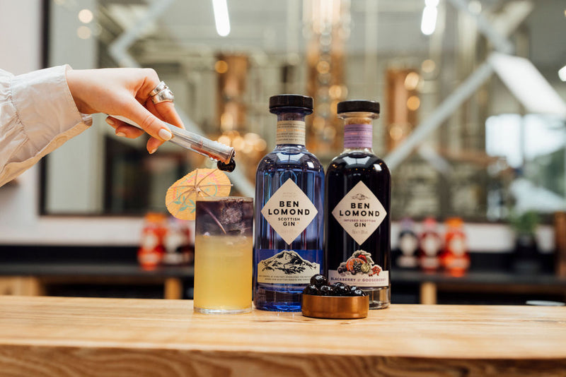 Two bottles of Ben Lomond Gin on a bar counter with a cocktail and a hand holding a cocktail spoon.