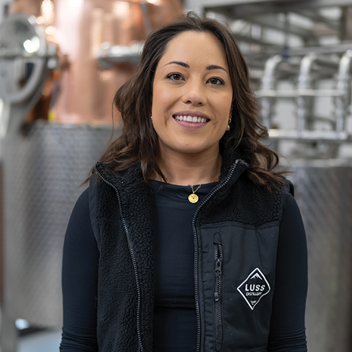 Woman wearing a black vest with a logo in an industrial setting