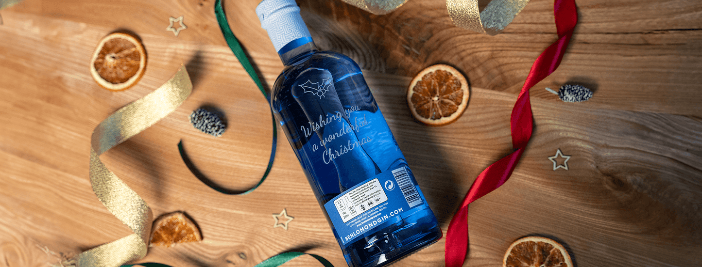 Blue bottle on a wooden surface with decorative ribbons and oranges