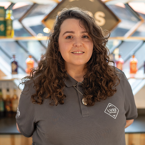 Woman wearing a gray polo shirt with a logo in an indoor setting