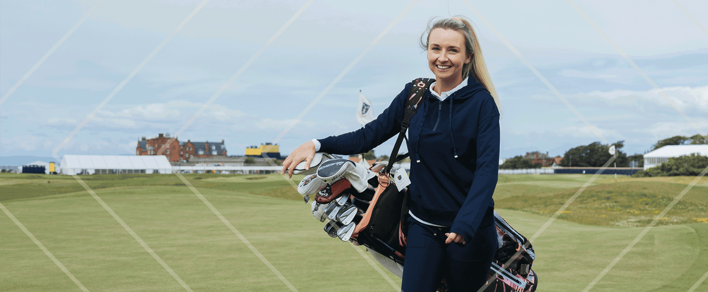 Woman standing on a golf course with golf bags and clubs.