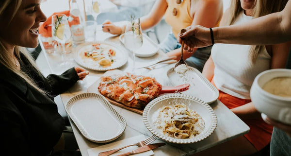 People enjoying a meal together at a restaurant with plates of food on a table.