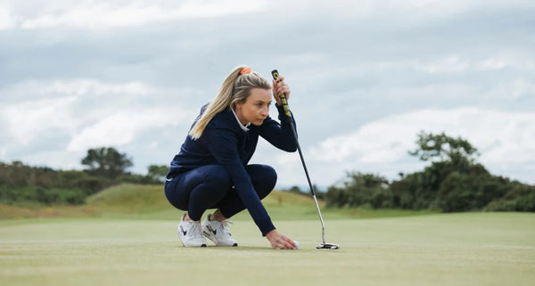 Woman on a golf course preparing to putt with a putter.