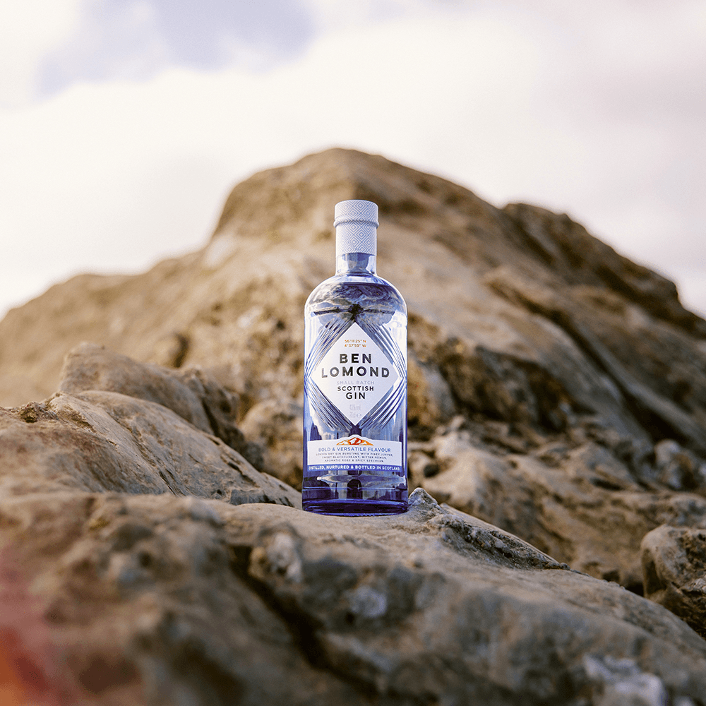 Bottle of Ben Lomond Scottish Gin on a rocky surface with a mountainous background