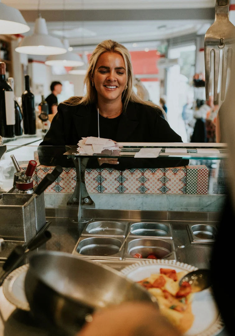 Person working behind a counter in a restaurant setting with food and condiments.