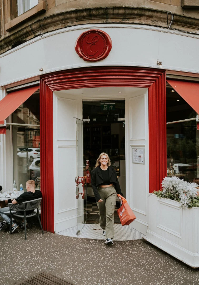 Woman walking out of a restaurant with a red logo on the door