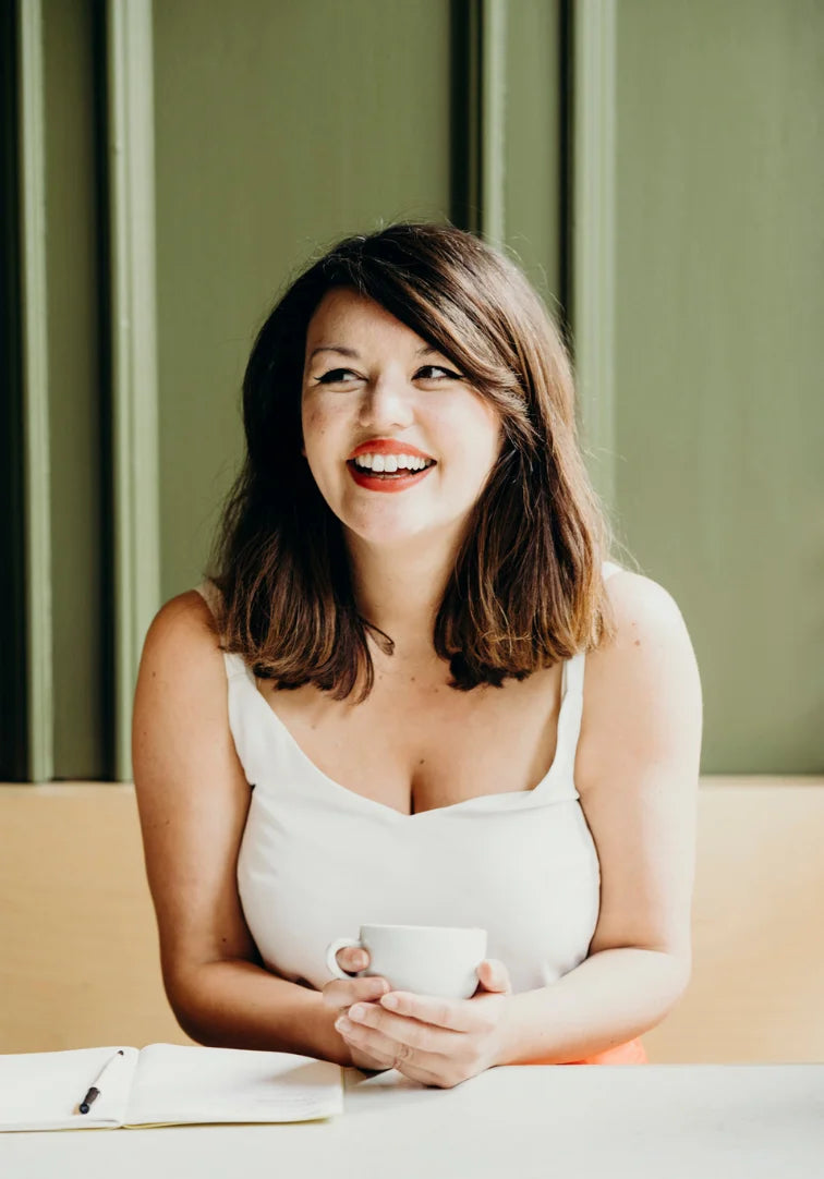Woman holding a cup and smiling in a casual setting