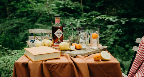 Table with drinks and snacks set up outdoors in a forest setting
