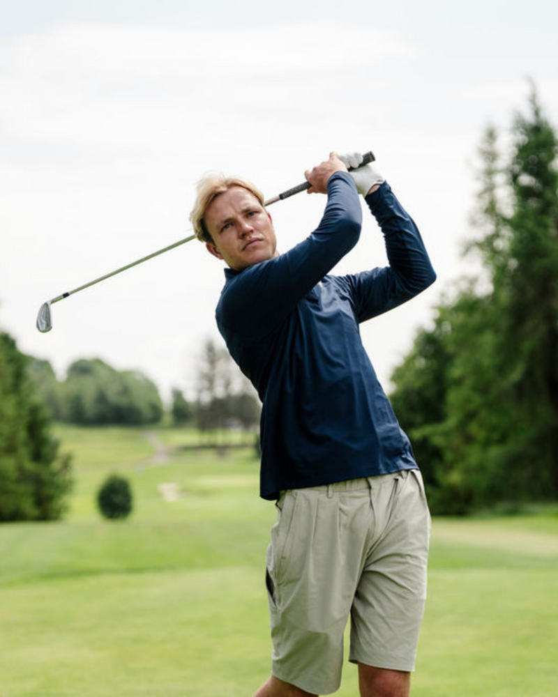 Man playing golf on a course with trees in the background