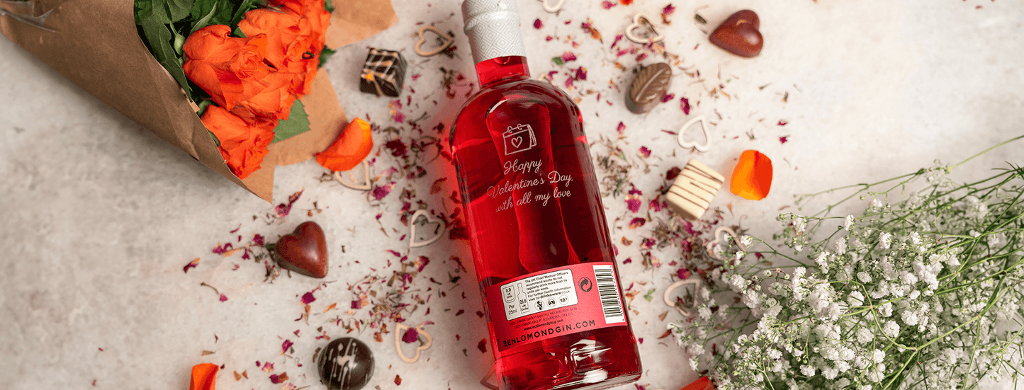 Red bottle with a label on a light surface with flowers and decorative elements